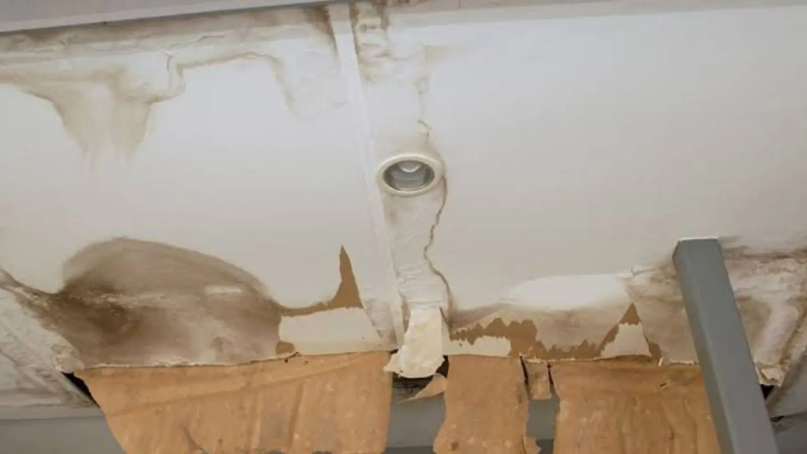 Water-damaged ceiling with sagging panels around a light fixture