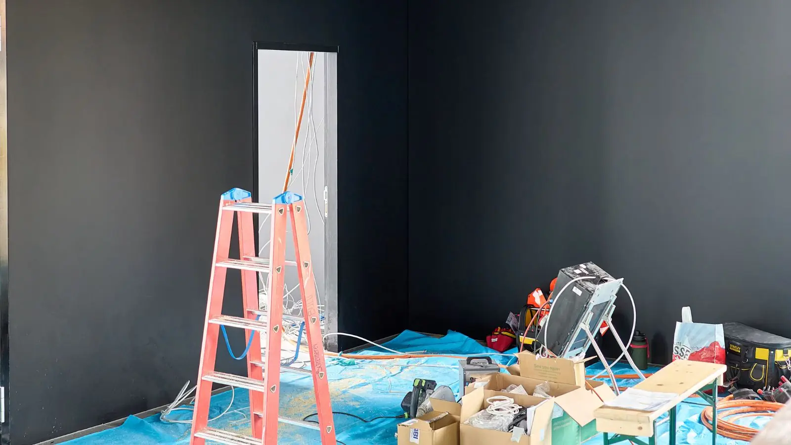 Room prepared for repair with a ladder, tarps and drying equipment